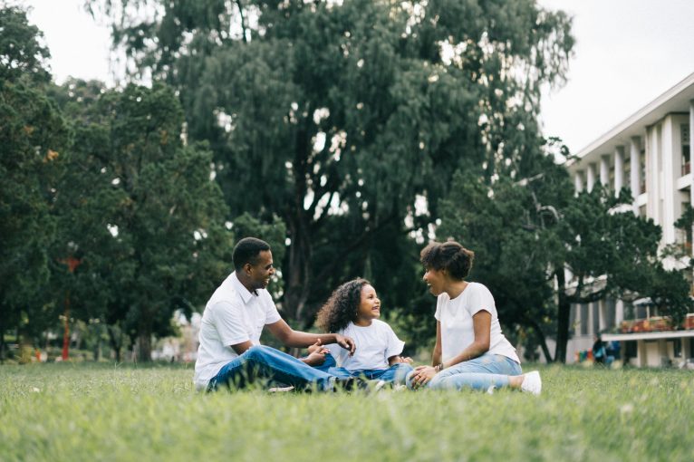 A happy black family enjoying quality time together outdoors in a lush green park.