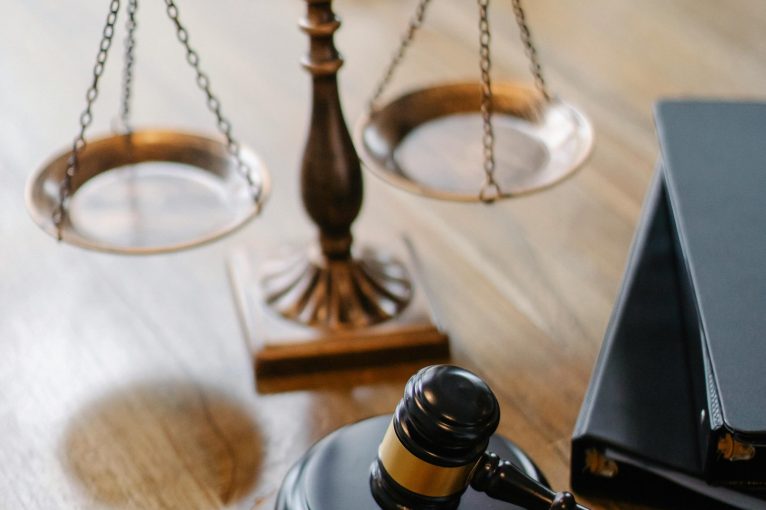 A striking image featuring a brass justice scale and gavel on a wooden desk, symbolizing law and justice.