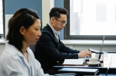 Two business professionals focused on laptops in a modern office setting.